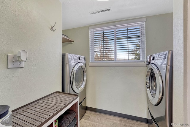 washroom featuring visible vents, light wood finished floors, baseboards, laundry area, and a textured wall