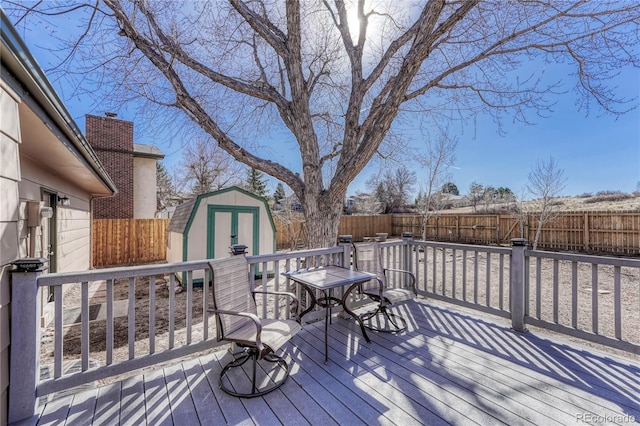 wooden deck featuring an outbuilding, a storage unit, and a fenced backyard