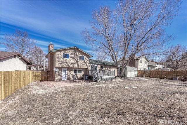 rear view of property featuring an outbuilding, central AC, a fenced backyard, a wooden deck, and a chimney