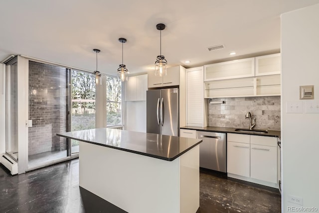 kitchen featuring hanging light fixtures, a kitchen island, white cabinetry, sink, and stainless steel appliances