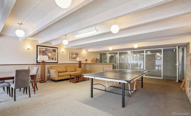 recreation room with beam ceiling, a textured ceiling, and carpet flooring