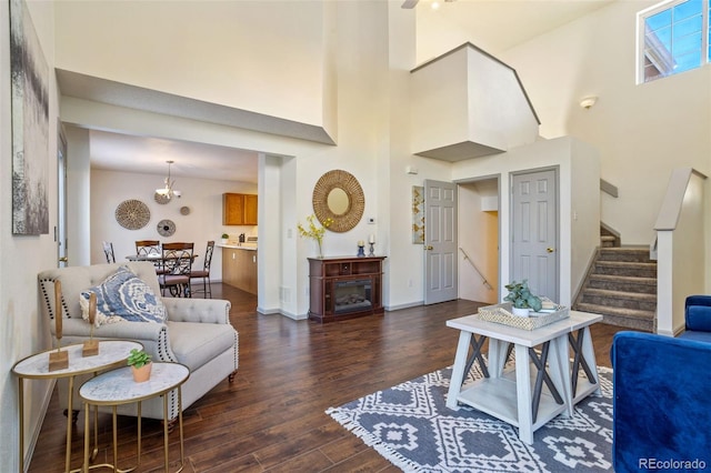 living room featuring a towering ceiling, dark hardwood / wood-style floors, and an inviting chandelier