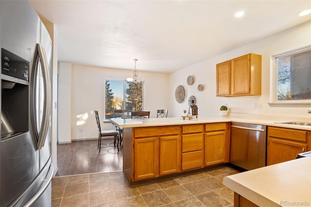 kitchen with kitchen peninsula, stainless steel appliances, sink, pendant lighting, and dark hardwood / wood-style floors