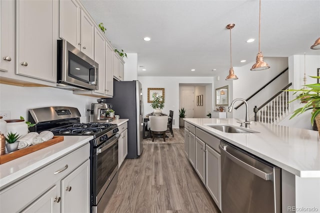 kitchen featuring sink, light hardwood / wood-style flooring, hanging light fixtures, a center island with sink, and stainless steel appliances