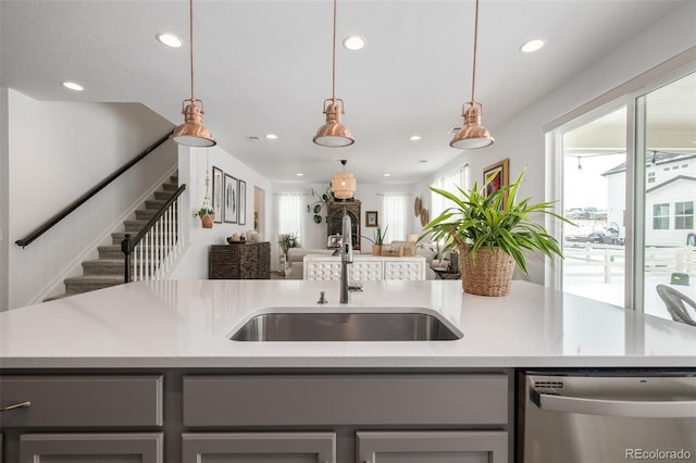 kitchen featuring sink, stainless steel dishwasher, hanging light fixtures, and an island with sink