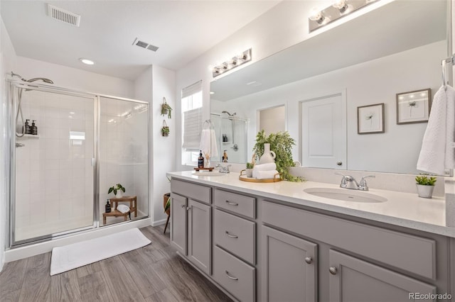 bathroom featuring hardwood / wood-style flooring, vanity, and an enclosed shower