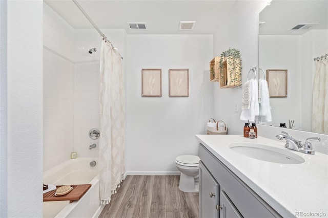 full bathroom with hardwood / wood-style flooring, vanity, shower / tub combo with curtain, and toilet