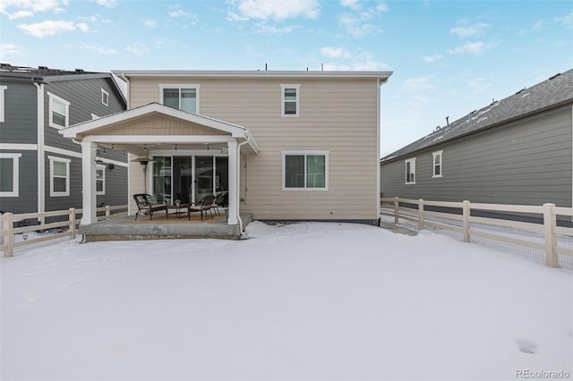 snow covered rear of property featuring covered porch