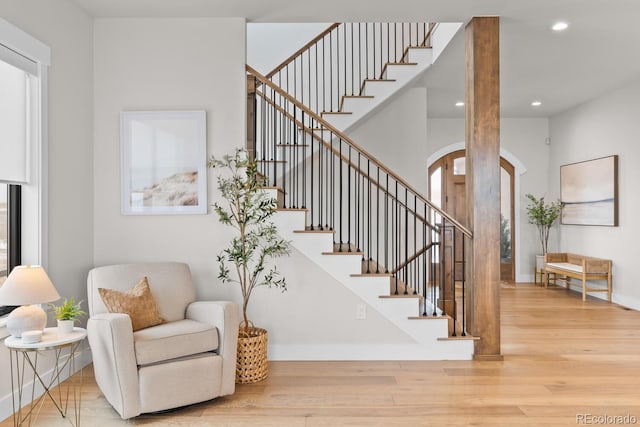 staircase featuring arched walkways, baseboards, recessed lighting, and wood finished floors