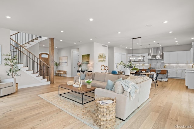 living area with light wood-style floors, visible vents, stairway, and recessed lighting