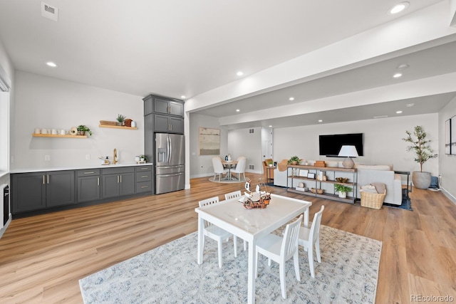 dining room with light wood-type flooring, visible vents, wet bar, and recessed lighting