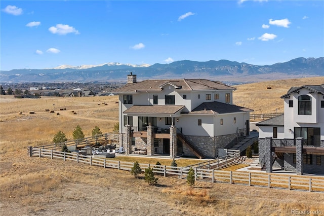 view of front of house featuring stucco siding, stairway, a mountain view, fence private yard, and stone siding