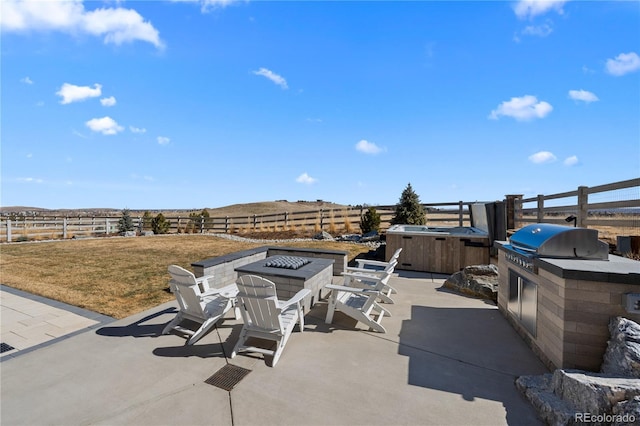 view of patio featuring an outdoor fire pit, fence, exterior kitchen, grilling area, and a hot tub