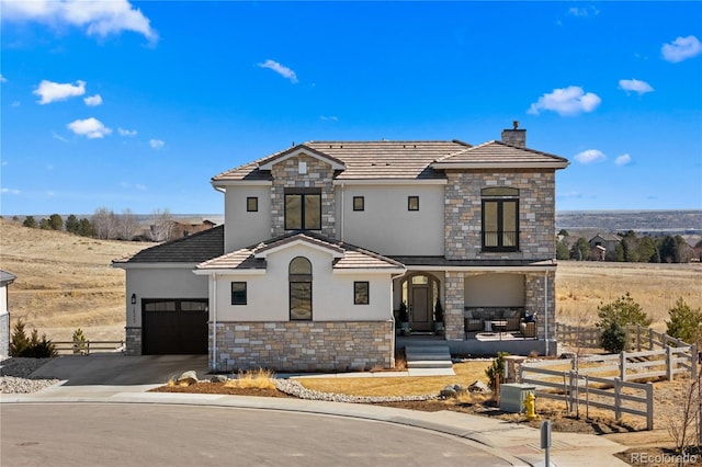 french country style house with a chimney, stucco siding, an attached garage, fence, and driveway