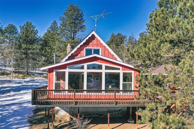 rear view of property featuring a sunroom and a wooden deck