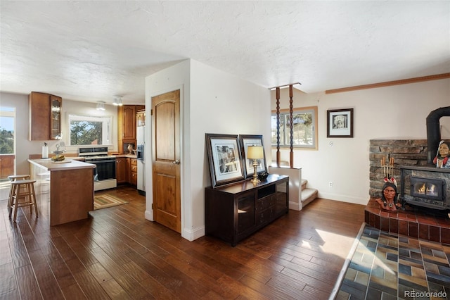 kitchen featuring a wood stove, dark hardwood / wood-style floors, a textured ceiling, range, and a breakfast bar area