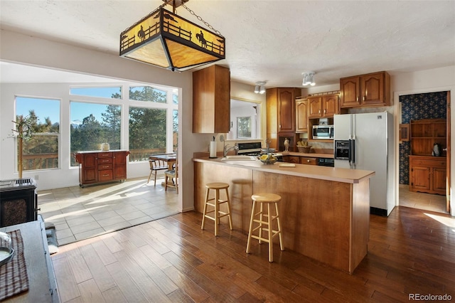 kitchen with a healthy amount of sunlight, light hardwood / wood-style floors, white refrigerator with ice dispenser, and kitchen peninsula