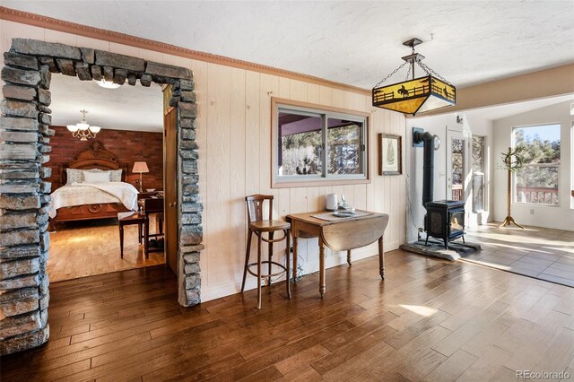 dining room with dark hardwood / wood-style floors, a wood stove, a wealth of natural light, and wooden walls