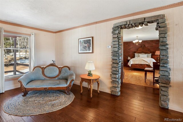 sitting room with dark hardwood / wood-style flooring, crown molding, a notable chandelier, and wood walls