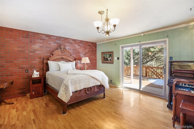 bedroom featuring access to exterior, light hardwood / wood-style flooring, ornamental molding, and an inviting chandelier