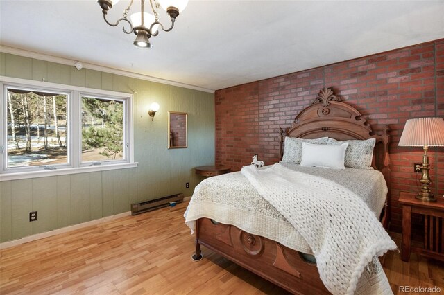 bedroom featuring light hardwood / wood-style floors, an inviting chandelier, brick wall, and a baseboard heating unit