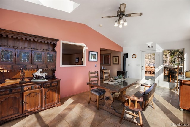 tiled dining area with ceiling fan and vaulted ceiling with skylight