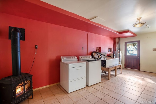 washroom featuring gas water heater, a wood stove, light tile patterned floors, and washing machine and clothes dryer