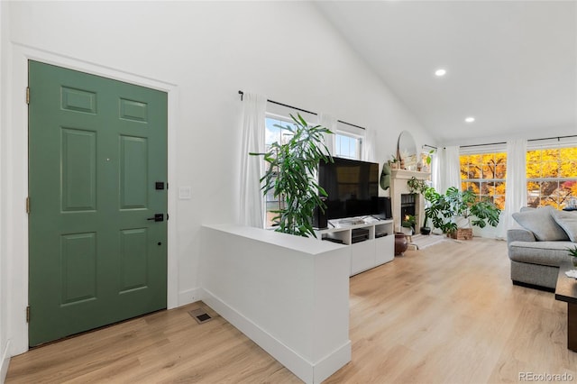 foyer with light hardwood / wood-style flooring and high vaulted ceiling