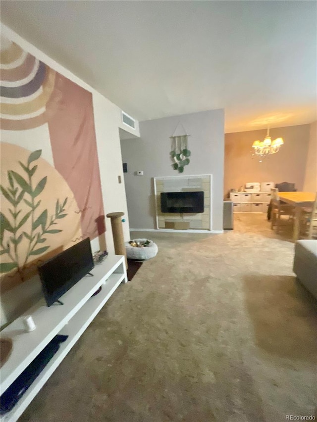 living room with a tiled fireplace, a notable chandelier, and carpet flooring