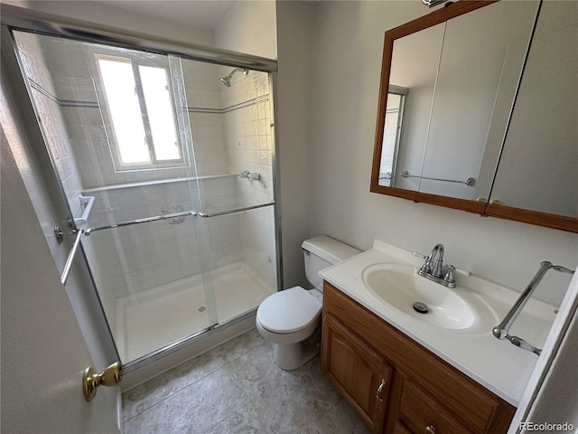 bathroom with toilet, vanity, and a shower with door