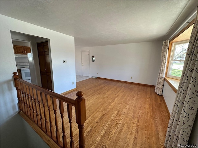 empty room featuring a textured ceiling and light hardwood / wood-style flooring