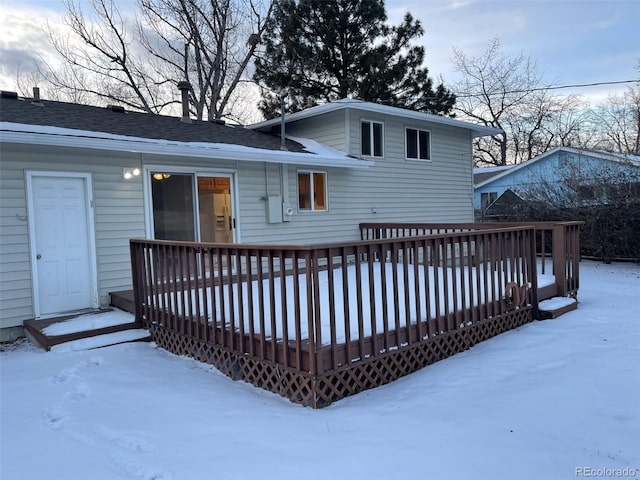 snow covered back of property featuring a deck