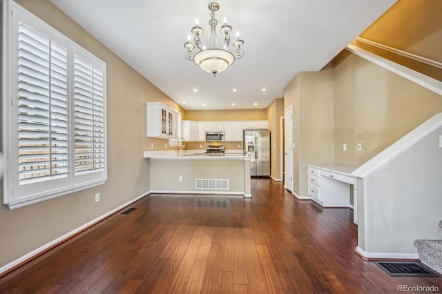 kitchen featuring white cabinets, kitchen peninsula, a chandelier, appliances with stainless steel finishes, and dark hardwood / wood-style floors