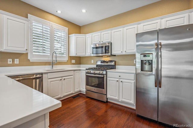 kitchen featuring white cabinets, appliances with stainless steel finishes, dark hardwood / wood-style floors, and sink