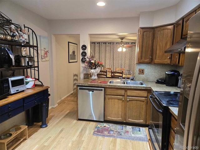 kitchen with a ceiling fan, light wood finished floors, a sink, appliances with stainless steel finishes, and backsplash