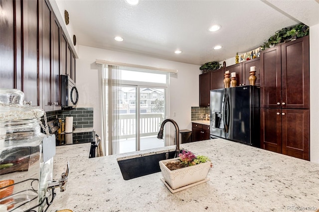 kitchen featuring stove, black fridge, sink, decorative backsplash, and light stone countertops