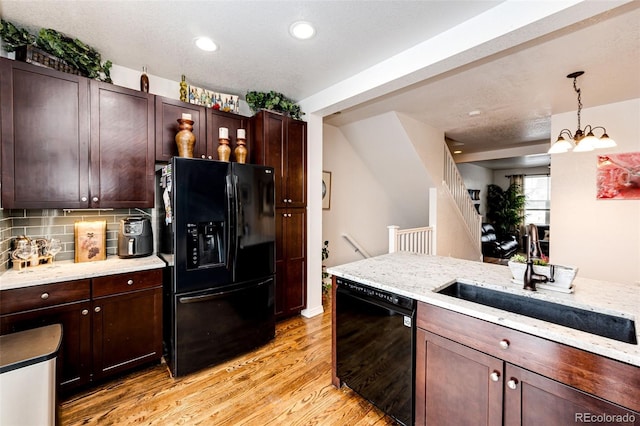 kitchen with black appliances, a sink, light wood-type flooring, decorative light fixtures, and recessed lighting