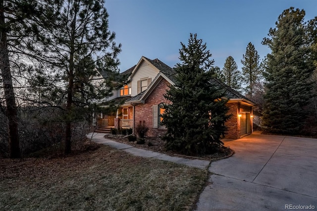 view of side of home featuring a garage, brick siding, and driveway