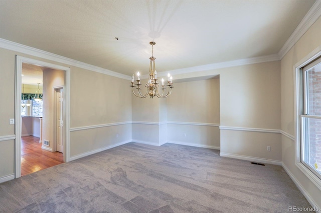 spare room with crown molding, carpet, visible vents, and a chandelier