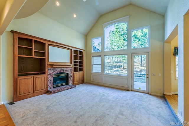 unfurnished living room featuring a brick fireplace, baseboards, carpet, high vaulted ceiling, and a ceiling fan