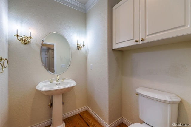 bathroom featuring toilet, wood finished floors, baseboards, and ornamental molding