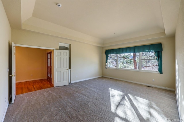 unfurnished bedroom with visible vents, a raised ceiling, and baseboards