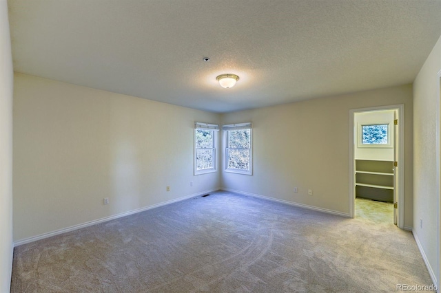 spare room with baseboards, carpet, and a textured ceiling