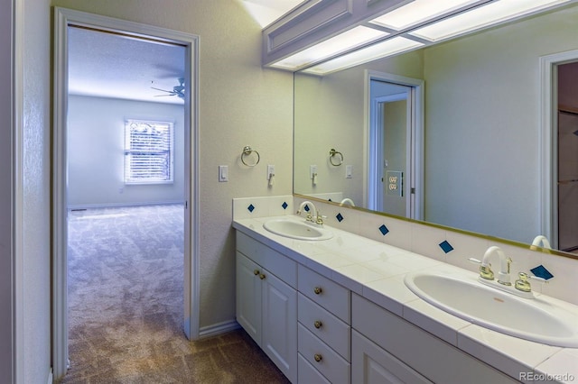 bathroom with double vanity, baseboards, and a sink