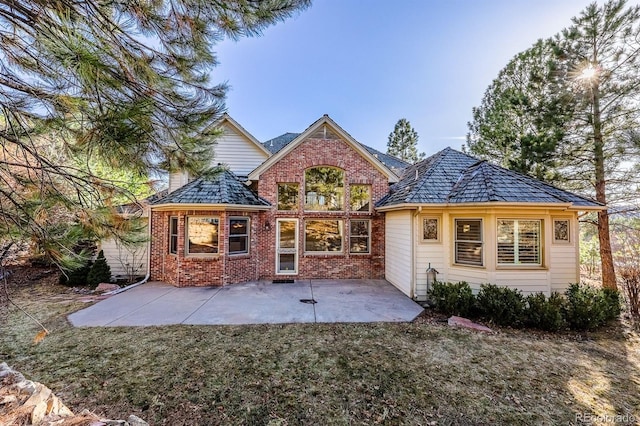 rear view of property featuring brick siding, a patio area, and a lawn