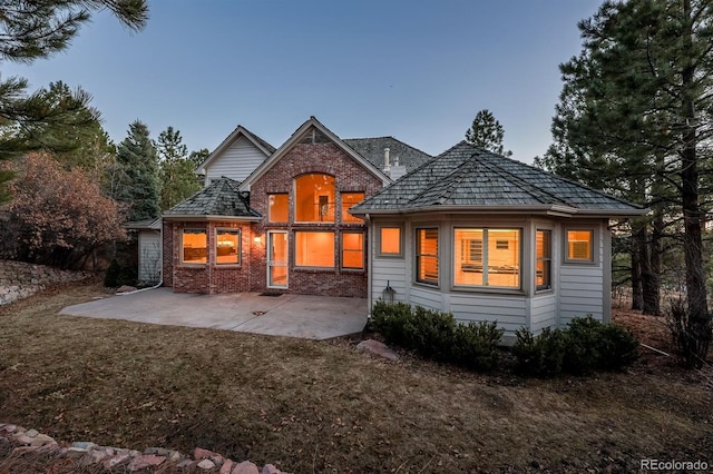 rear view of house with a yard, brick siding, and a patio area