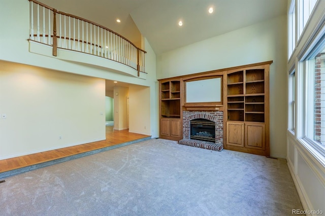 unfurnished living room featuring recessed lighting, carpet floors, high vaulted ceiling, and a brick fireplace