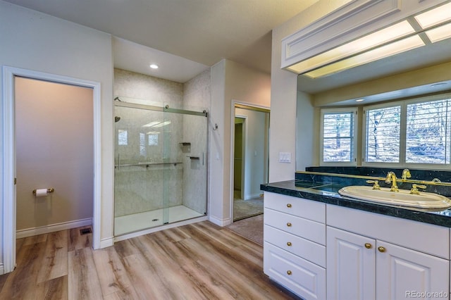 bathroom with a stall shower, vanity, baseboards, and wood finished floors