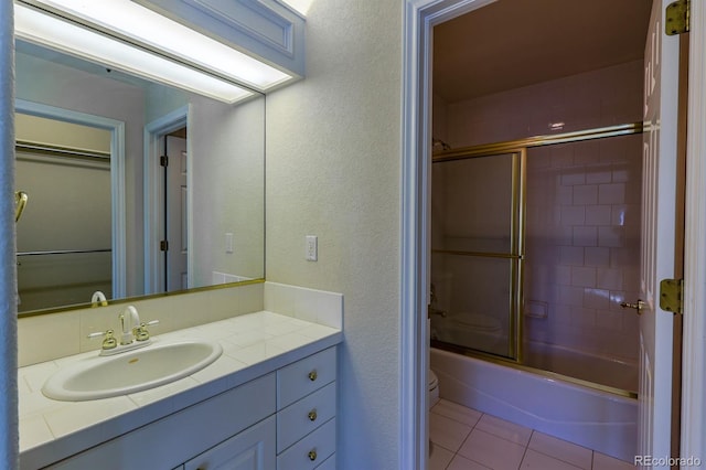 full bathroom with tile patterned floors, toilet, shower / bath combination with glass door, vanity, and a textured wall