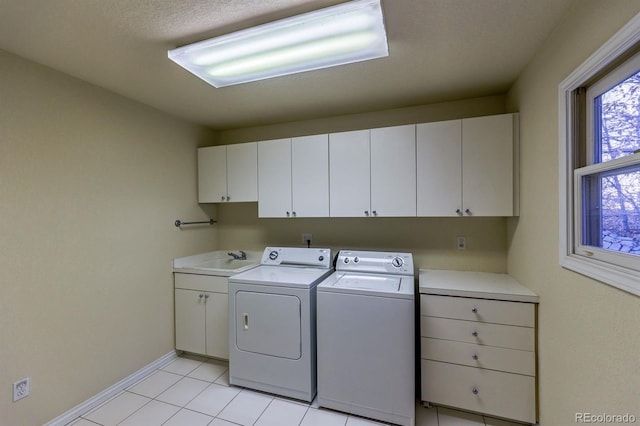 laundry room with washing machine and clothes dryer, baseboards, light tile patterned floors, cabinet space, and a sink